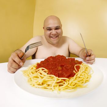 An overweight man enjoying a plate of spaghetti.  Shot with fish-eye lens.  Focus is on the face.
