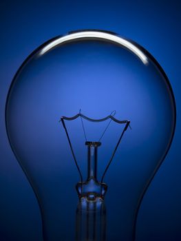 Close up on a transparent light bulb over a blue background.