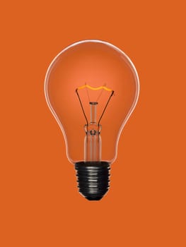 A transparent light bulb over an orange background. Tungsten glowing filament.