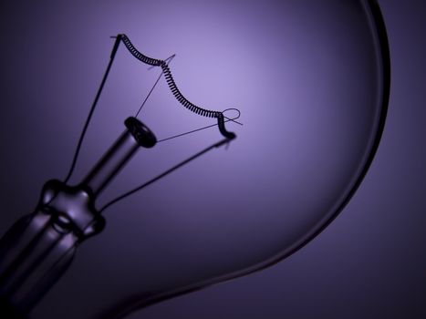 Close up on a transparent light bulb over a purple background.