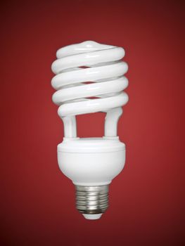 Compact fluorescent light bulb over a red background.