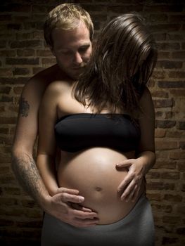 A man holding his pregnant wife's belly.
