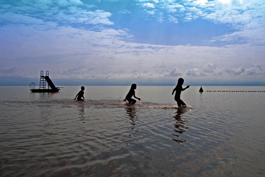 silhouetted kids walking in the water, photoshopped