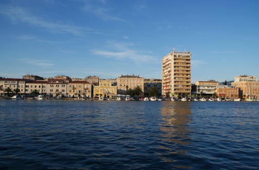 The view across the sea to the city. With a blue sky in the background.