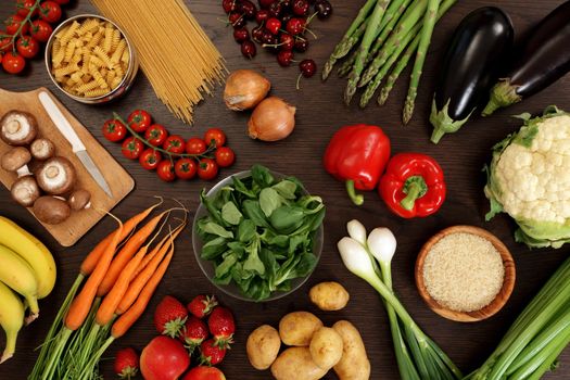 Photo of a table top full of fresh vegetables, fruit, and other healthy foods.