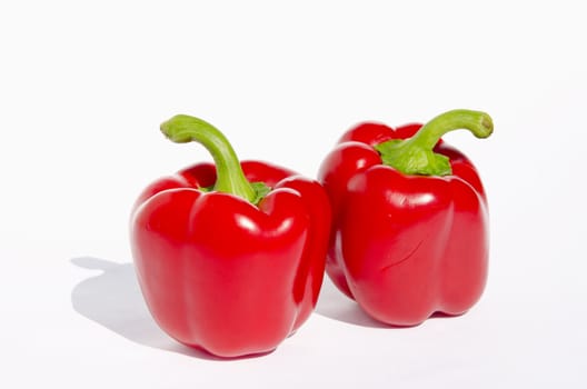 Ecological and healthy food. Two red papricas with green branches on a white background.