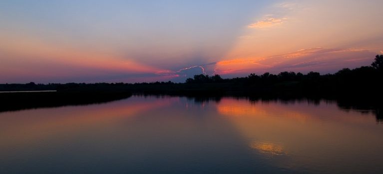 Dawn sunbeams emerge over lake Mitchell, South Dakota