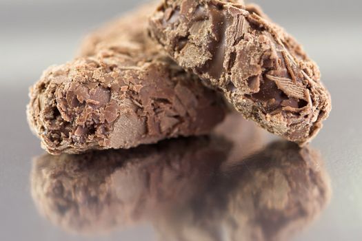 Chocolate truffles on reflective background, three together