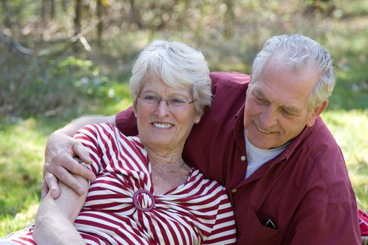 Lovely elderly couple enjoying each others company outdoors in the sun on a summer day