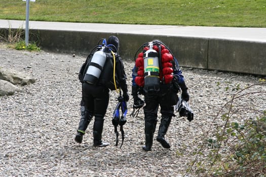 Scuba Divers is a capture of two divers that have just finished their lesson and are walking back across a rocky beach. 
