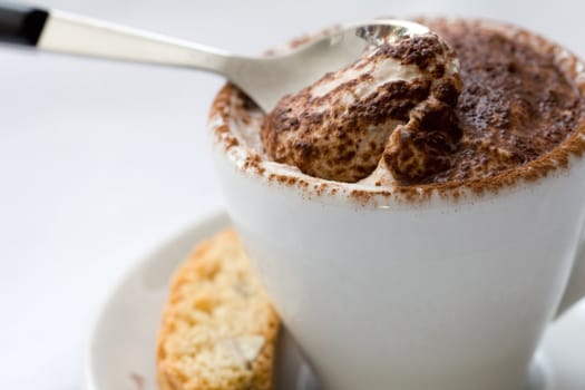 Delicious creamy dessert with a spoon in it served in a small coffeecup