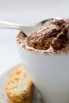 Delicious chocolate dessert with spoon served in a coffee cup with a cookie next to it