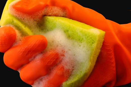 Soapy sponge held by a hand in an orange protective glove