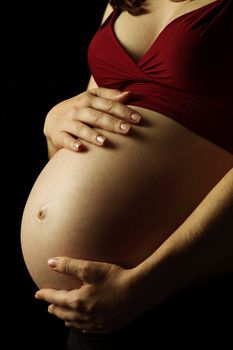 Photo of a pregnant female with her hands on her belly.