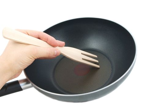 Frying pan with wooden spatula, isolated with human hand towards white background