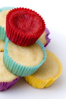 Plate of small undecorated cupcake in multicolored paper cup