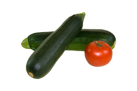 Two green vegetable marrows and tomato on the white