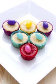 small cupcake in multicolored paper cup decorated by a color matching candy