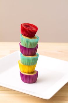 small cupcake in colorful cup place one on top of the other to create a column 