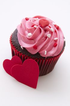 Chocolate cupcake decorated with pink frosting and candy hearts