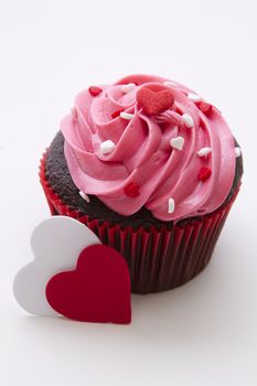 Chocolate cupcake decorated with pink frosting and candy hearts