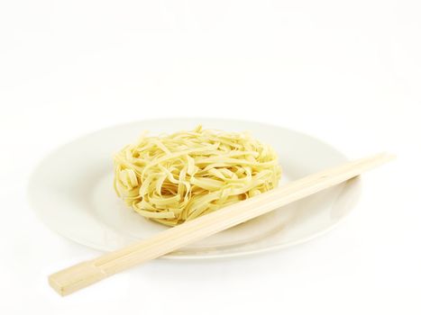 Dried uncoocked noodles, on white plate with chopsticks, isolated towards white background