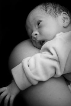 Newborn on mothers shoulder in black and white