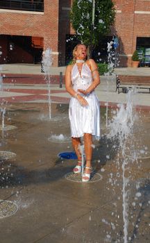 attractive blonde woman having fun in the water outdoors at the park