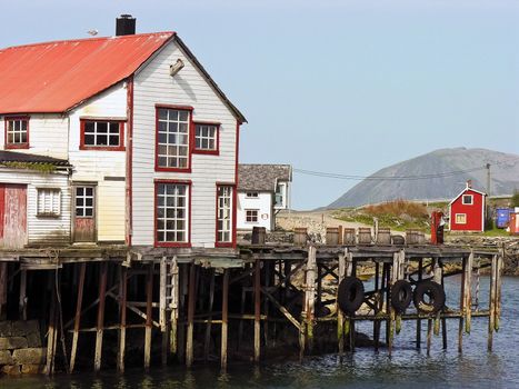 Old ruined red and white wooden nordic house over a river in Norway