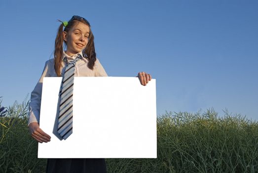 Teen girl holding white poster at green field