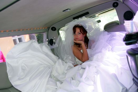 Sad young bride in wedding car limousine.