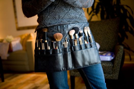 Image of a make-up artist wearing a belt with brushes on it ready to work