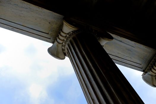 The top of a white stone column with groves and designs against sky.