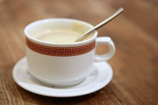 Coffe with milk white cup over teak wooden background