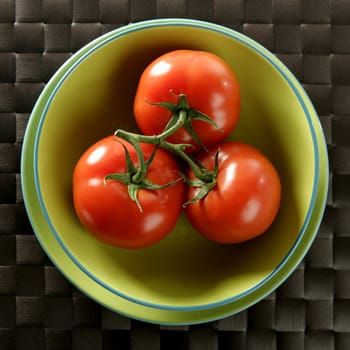 Three red tomatoes in the same one branch over a green plate