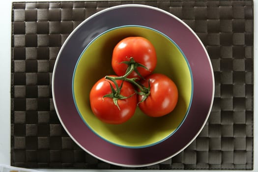 Three red tomatoes in the same one branch over green plate