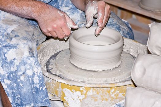 craftsman spinning a vase from clay on a pottery wheel
