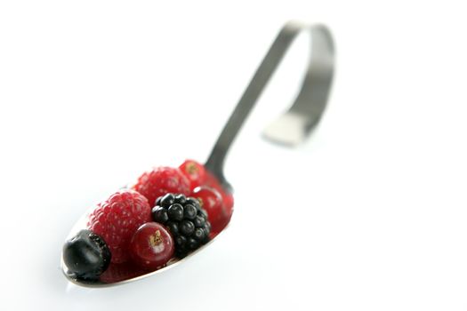 Varied berries in a curved spoon in white background