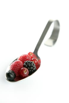 Varied berries in a curved spoon in white background
