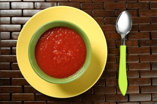 Tomato soup in colorful green dish over wood