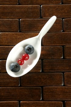 Berries in a white spoon, wooden background