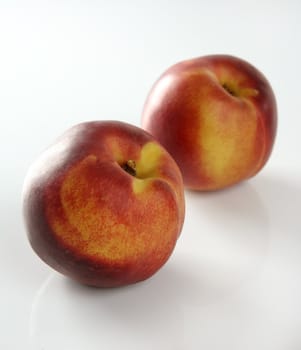 Summer fruits, two red peaches over white studio background