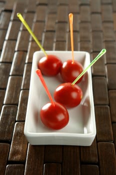 Tomatoes snack in a white dish and colored sticks