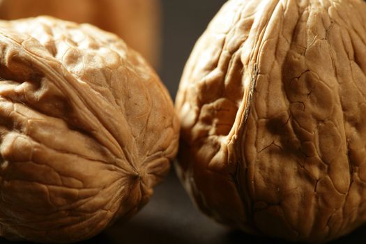 Three walnuts with shells over black background and shadows