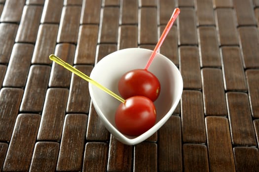 Tomatoes snack in a white dish and colored sticks