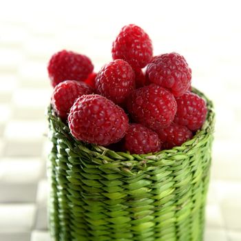 A group of fresh raspberries in a green little basket