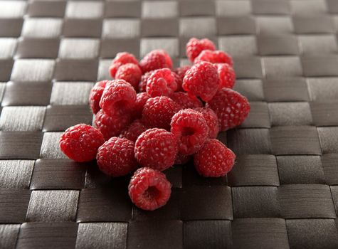 A group of fresh raspberries over brown tablecloth