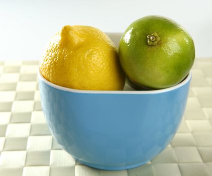 Two lemon and lime in a blue bowl, one yellow and another green