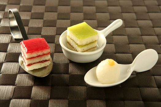 Varied pastries over spoon. Little colorful cakes