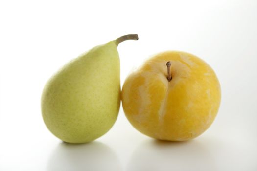 Close up of yellow Mirabelles and Pear on white studio background